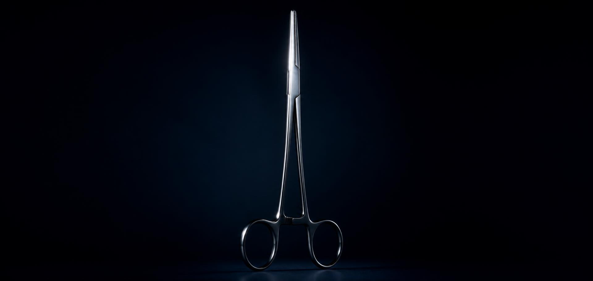 Precision stainless steel forceps lit against a dark background