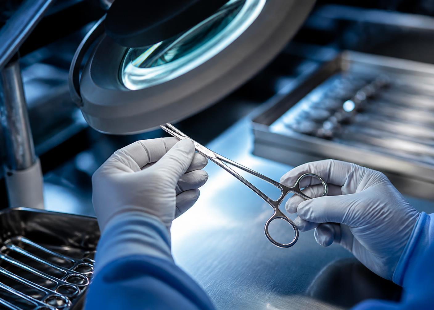 Finished forceps inspected under a magnifier at the quality bench